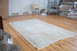 Allover distressed character and worn texture in muted ivory, beige, and rose.