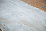 Distressed Oushak rug with muted ivory, beige, and grey worn pile texture.