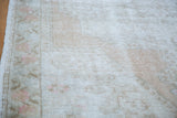 Worn texture of distressed Oushak rug showing muted ivory, beige, and subtle rose.