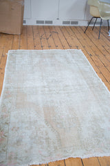 Distressed Oushak rug, showing worn texture, muted ivory, beige, and subtle rose patterns.