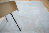 Distressed Oushak rug's worn texture, showing muted ivory, beige, and subtle rose.