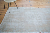 Distressed vintage Oushak rug edge showcasing worn texture and subtle rose pattern.