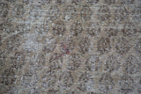 Distressed vintage Oushak carpet pile showing faded brown, ivory, and grey motifs.