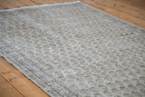 Angled view of distressed Oushak rug showing faded allover pattern and subtle texture.