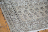 Faded distressed texture and border motifs of the vintage Oushak carpet in charcoal and pale green.