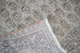 Distressed Oushak pile in grey and faded green, exposing hand-knotted back and fringe.