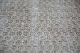 Distressed Oushak rug displaying faded allover patterns in grey, charcoal, and subtle green.