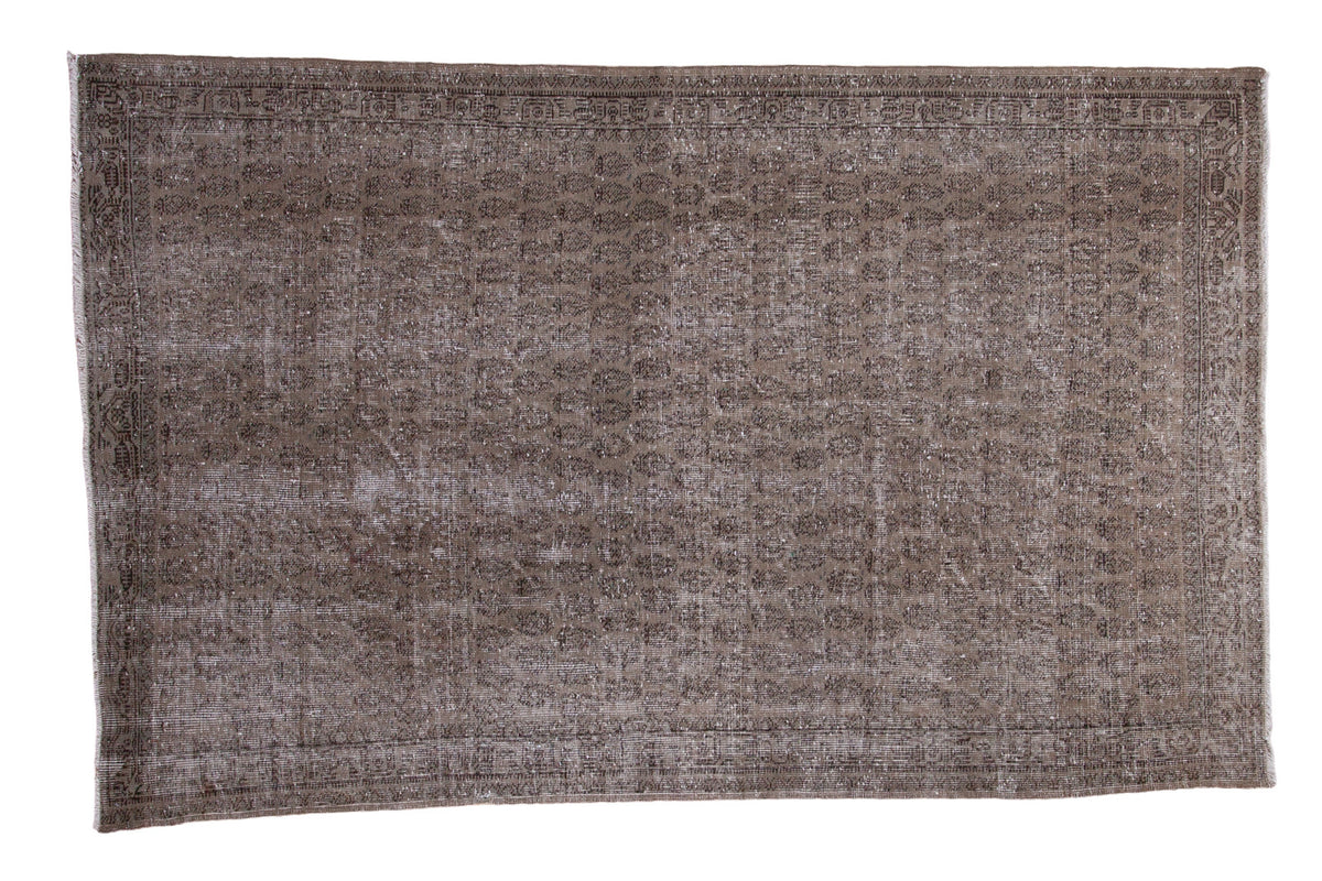 Heavily distressed Oushak carpet featuring a faded allover design in grey, charcoal, and green, 4'10" x 7'8".