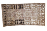 Distressed Oushak runner rug with geometric patterns, contrasting darks, and exposed foundation.