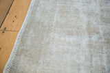 Distressed hand-knotted Oushak rug texture, showing exposed foundation in soft grey.