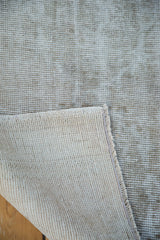 Distressed Oushak rug corner revealing exposed foundation and tight woven back.