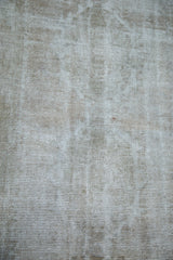 Distressed texture and exposed foundation of a vintage Oushak rug in silver and grey tones.