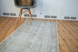 Distressed Oushak rug with visible low pile texture and muted silver-grey tones.