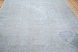 Distressed Oushak rug texture showing recessed wool, subtle grey, and hints of rose.