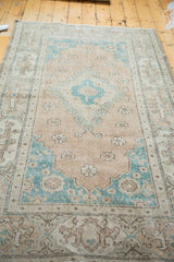 Distressed pile texture of a vintage Oushak rug, showing peach apricot and aqua patterns.