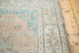 Distressed Oushak rug corner, showcasing decorative texture in peach and aqua green.