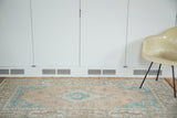 Distressed corner of a vintage Oushak rug, showing faded peach apricot field and aqua spandrel.