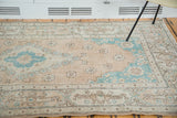 Distressed Oushak rug corner: faded peach apricot field, aqua spandrel, decorative border.