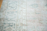 Distressed vintage Oushak carpet, blush field with silvery grey and bronze scrolling vine patterns.