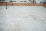 Distressed Oushak carpet texture with muted blush, silvery grey, and ivory geometric motifs.