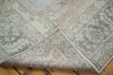 Distressed Oushak rug corner showing geometric blush, grey pile and intricate reverse weave.