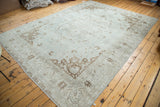 Decorative corner of a distressed Oushak rug, featuring sea foam green and chocolate tones.