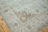 Soft distressed Oushak carpet corner, sea foam green field, charcoal brown curvilinear motifs.