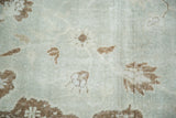 Close-up of distressed Oushak rug pile with soft sea foam green and coffee bean chocolate tones.