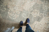 Distressed Oushak carpet with faded forest green field and intricate blush rose floral details.