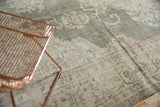 Distressed texture of vintage Oushak rug showcasing faded forest green and ivory floral motifs.