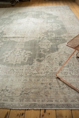 Textured distressed Oushak rug displaying faded forest green and ivory floral motifs.