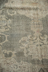 Faded green field and textured beige floral motifs on distressed Oushak rug.
