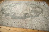 Distressed Oushak carpet detail: faded green field, beige border, blush rose florals.