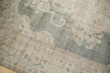Distressed Oushak carpet showing faded forest green field and intricate floral border.
