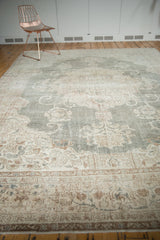 Distressed hand knotted Oushak carpet with faded ivory, beige, and green floral patterns.