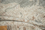 Distressed Oushak carpet close-up, showing faded floral motifs in ivory, beige, light bronze.