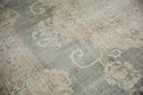 Distressed Oushak carpet pile showing faded forest green field and blush floral motifs.
