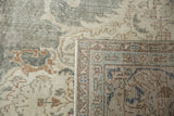 Distressed Oushak rug corner revealing faded green pile, hand-knotted foundation, and detailed border.
