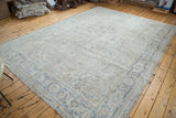 Angled view of distressed Oushak carpet with blanched ivory and grey Heriz-style design.