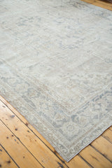 Distressed vintage Oushak rug corner showing blanched ivory, silver, and grey patterns.