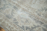 Close-up of distressed Oushak carpet, showing blanched ivory, silver-grey, and faded patterns.