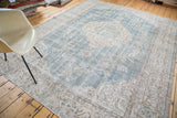 Distressed ivory and light beige border with intricate floral patterns, faded blue field.