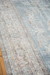 Distressed Oushak carpet texture, faded slate blue field, beige floral border.