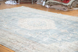 Distressed texture of a slate blue Oushak rug with faded ivory floral motifs.