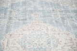 Distressed texture and ornate apricot floral motifs on faded slate blue Oushak rug.