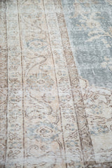 Distressed texture highlighting faded floral motifs on a vintage Oushak in slate blue and beige.