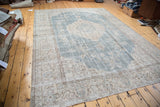 Faded slate blue distressed Oushak corner with intricate light beige floral border.