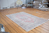 Distressed Oushak rug featuring faded raspberry red field and curvilinear sky blue details.