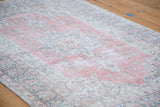 Faded raspberry and sky blue curvilinear motifs on a distressed vintage Oushak rug.