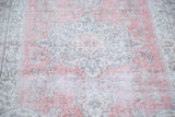 Distressed faded raspberry red Oushak rug pile with sky blue and ivory curvilinear motifs.